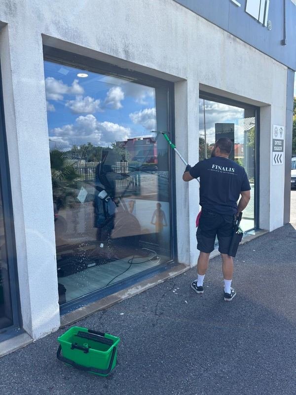 Nettoyage de la vitrine d'un magasin à la perche